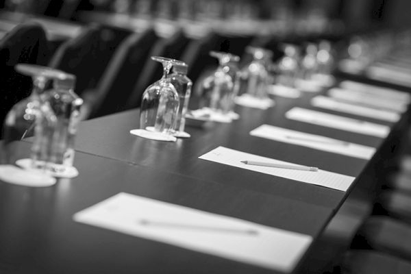 A conference table set with notepads, pens, and upside-down glasses neatly arranged.